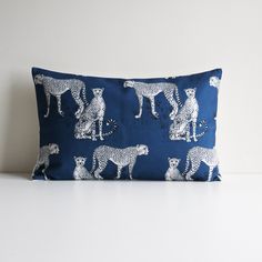 a blue pillow with white cheetah and leopards on it, sitting on a table