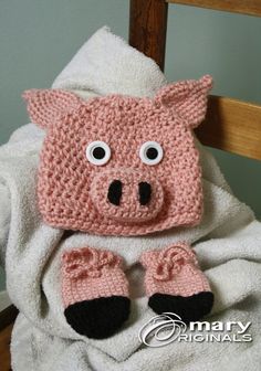 a knitted pig sitting on top of a white blanket next to a wooden chair