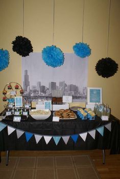 a table topped with donuts and desserts under blue pom - poms