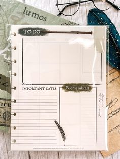 an open planner book sitting on top of a table next to eyeglasses and other items