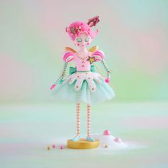 a pink and blue figurine wearing a tiara with pearls on it's head