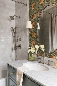 a white sink sitting under a bathroom mirror next to a bathtub and shower head