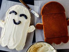 a cake shaped like a ghost next to a bowl of whipped cream and a knife