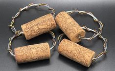 four corks with beaded cord and beads around them on a black table top