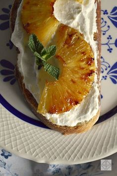 a piece of bread topped with whipped cream and sliced pineapple on a blue and white plate