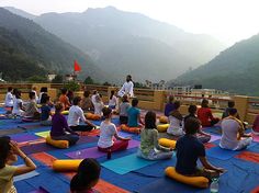 a group of people sitting on top of yoga mats in the middle of a mountain