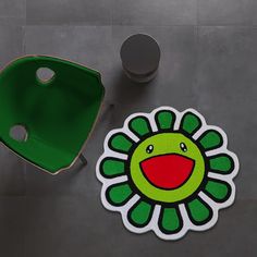 a green chair sitting next to a flower shaped rug on top of a gray floor