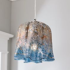 a blue and gold lamp hanging from a ceiling in a room with a white fireplace