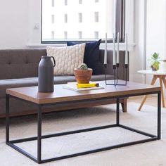 a living room with a couch, coffee table and vase on the floor in front of a window