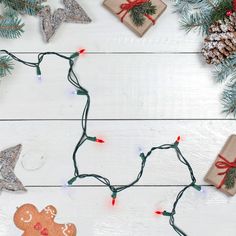 christmas decorations and presents are arranged on a white wooden table with pine cones, twine lights, and small ornaments