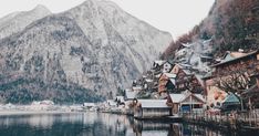 a village on the shore of a lake with mountains in the background