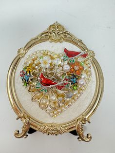 a gold plate with birds and pearls in the shape of a heart on white background