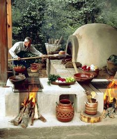 a man is cooking food outside in front of an outdoor oven and fire pit with pots on it