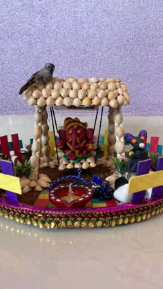 a carousel made out of rocks and other items on a white counter top with a purple wall in the background