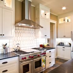 a kitchen with white cabinets and stainless steel stove top oven in the middle of the room