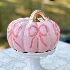 a pink painted pumpkin sitting on top of a white cake plate