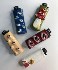 four lighters with eyes painted on them sitting next to each other