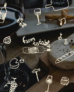 a glass of wine and some food on a wooden board with words written in it