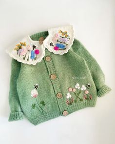 a green sweater with embroidered flowers on it