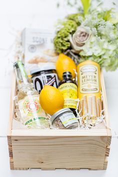 a wooden box filled with lemons, honey and other condiments next to flowers