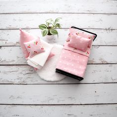 pink and white bedding with polka dot print on the comforter, pillows and potted plant