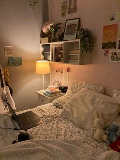 a laptop computer sitting on top of a bed next to a stuffed animal and lamp