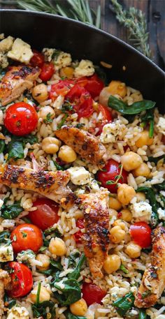 a skillet filled with chicken, rice and tomatoes