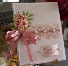 a close up of a card on a table with flowers and ribbon around the edges