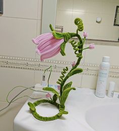 a pink flower sitting on top of a bathroom sink next to a white countertop