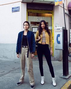 two women standing on the sidewalk in front of a building