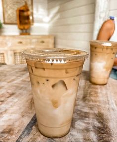 two plastic cups sitting on top of a wooden table next to a person in the background