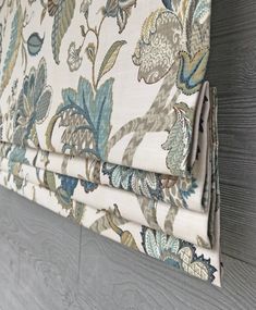 an upholstered window with blue and green floral fabric on it's side