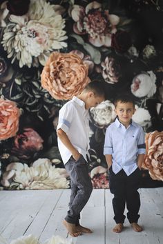 two young boys standing in front of a floral wall