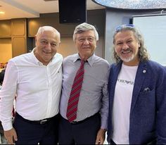 three men standing next to each other in front of a tv screen with the caption's name on it