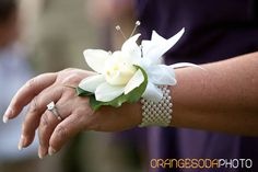 a close up of a person's hand holding a flower on her wrist with other people in the background