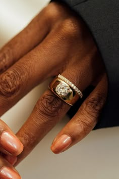 a close up of two hands holding an engagement ring