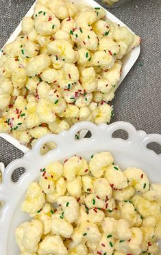 two white bowls filled with popcorn and sprinkles on top of a table