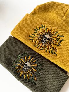 two beanies with sunflowers on them sitting next to each other in front of a white background