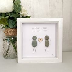 two pebbles holding hands in a white frame