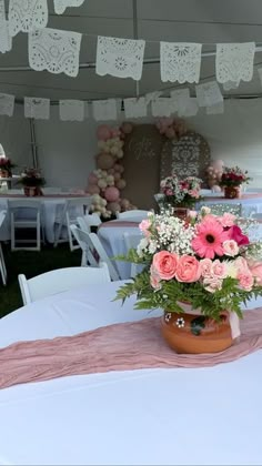 a vase filled with flowers sitting on top of a table covered in white linens