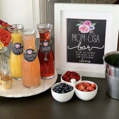 a table topped with drinks and fruit next to a framed sign that says mom - osa bar