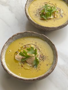 two bowls filled with soup sitting on top of a white countertop next to each other