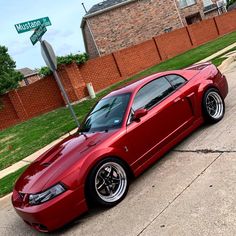 a red sports car parked on the side of the road in front of a brick building