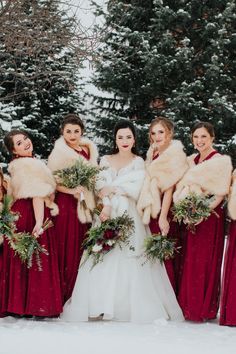 the bride and her bridesmaids are dressed in red dresses with fur stoles