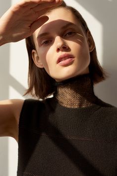 a young woman is posing for the camera with her hand on her head and wearing a black turtle neck top