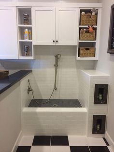 a bathroom with black and white tile flooring, cabinets, and a shower head