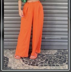 a woman standing in front of a garage door wearing an orange pants and green top