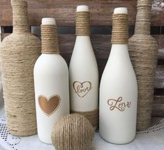 three white bottles with hearts on them are sitting next to a ball and twine