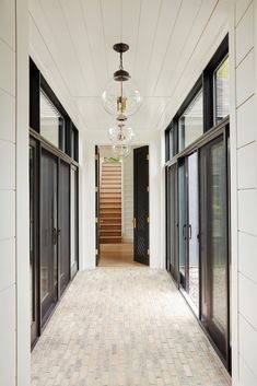 the hallway is lined with black doors and windows, along with a chandelier hanging from the ceiling