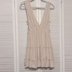 Nwt Arm Pits Have Criss Cross Tied. The Back Has Strings To Tie To A Bow. Beige Sleeveless Mini Dress With Tie Straps, Sleeveless Beige Dress With Tie Back, Cream Sleeveless Mini Dress For Summer, Cream Sleeveless Sundress For Brunch, Cream Sleeveless Sundress For Beach, Cream Sleeveless Sundress, Bohemian Beige Sleeveless Mini Dress, Sleeveless Neutral Mini Dress For Summer, Neutral Sleeveless Mini Dress For Summer